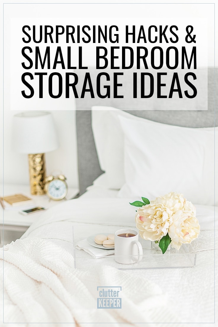 Surprising Hacks and Small Bedroom Storage Ideas, A bed with an upholstered headboard from the front with pillows and a fluffy comforter pulled slightly back. On top of the bed is a tray with a small plate of macarons, a cup of coffee and flowers. Next to the bed is an old fashioned alarm clock and a small lamp on a bed side table used for storage in a small bedroom..