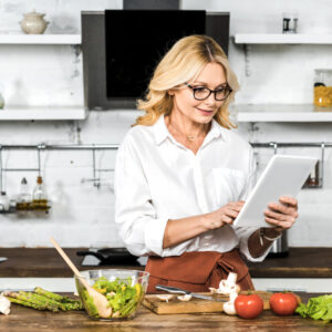 A woman uses the Easy Recipe Depot app on a tablet to make a salad.